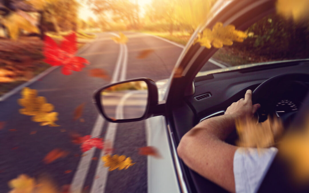 Man driving car in the fall autumn leaves with the Benefits of Seasonal Car Maintenance 